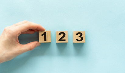 Close-up of a man holding a wooden block numbered one, two and three on a wooden table. concept wins