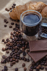 Cup of coffee and croissant with chocolate on paper background