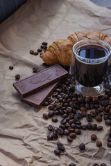 Cup of coffee and croissant with chocolate on paper background