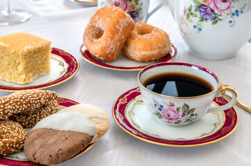 Breakfast detail. Cookies on a small plate nad cup of black coffee. Close up photo. 