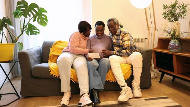 pregnant mother with grandparents on sofa, african americans, they are watching sonogram of baby
