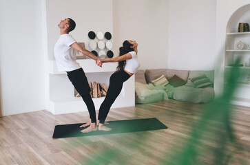Flexible couple stretching in yoga pose in living room