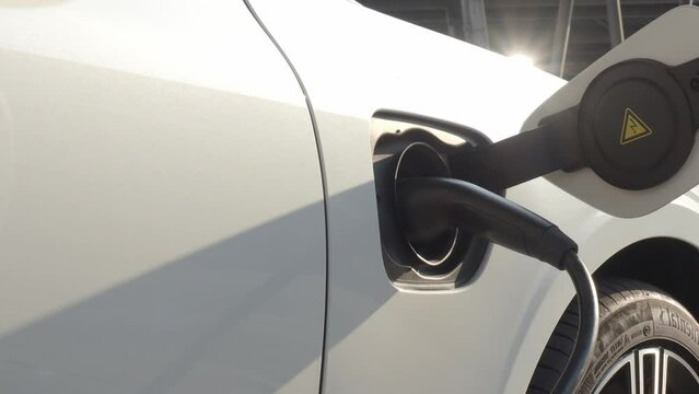 Charging EV car. Using EV charger quick charge type at car parking which is future transport energy technology. EV Charger car station charging use AC or DC socket plug for electric engine vehicle.