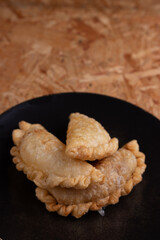 Empanada frita argentina, sobre plato redondo Negro