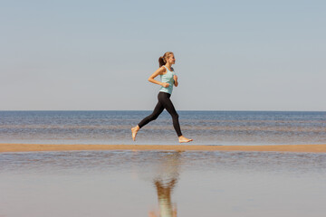 jogging, sporty woman runs in morning on seashore. fitness millennial female trains for marathon, healthy lifestyle, love for her body, mental and physical condition, sportswear, champion