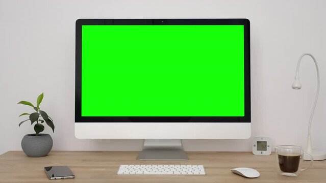 Green Mock-up Screen Desktop Computer with Mouse Keyboard Wide Standing on Desk Ficus flower in pot, table lamp in Office on White Wall Background. Zoom in footage slide View from forward. Chromokey. 
