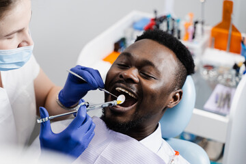 Dentist injects syringe with anesthesia in mouth of african man for treatment of diseased teeth. Caries treatment. Anesthesia syringe injection.