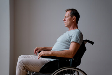 Senior man sitting on the wheelchair near the wall