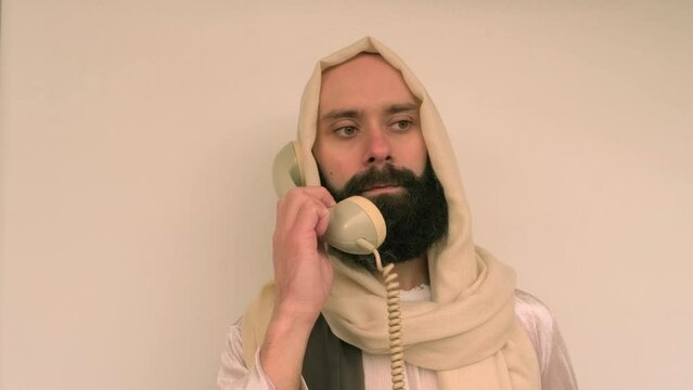 young pensive bearded and mustachioed man, guy with 30 years old in image of Savior, Jesus Christ holding landline phone, ask follow or following offer, offering, communication with people, helpline