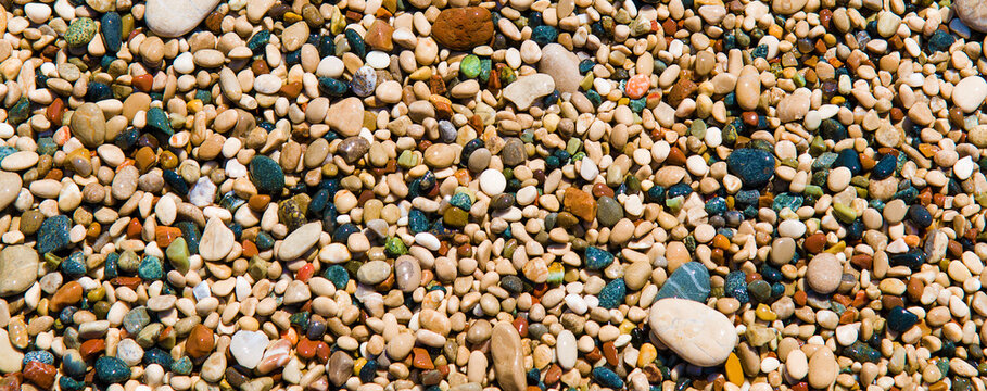 Multi-colored pebbles on the beach of the mediterranean sea. Wide photo.