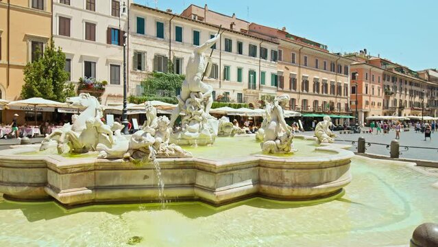 Tourists visit the Elegant square with baroque fountains and street artists. The famous Statue of the God Zeus in Bernini's Fountain of the Four Rivers in the Piazza Navo