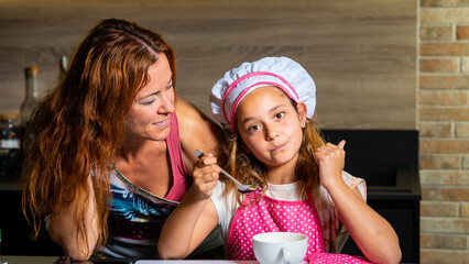 Mother and daughter dressed as a cook in the kitchen
