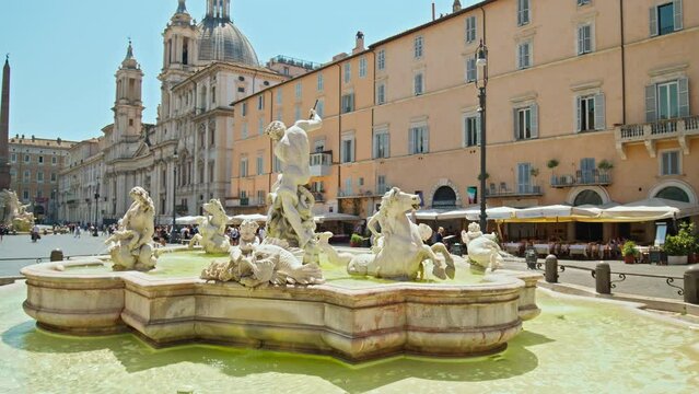 Tourists visit the Elegant square with baroque fountains and street artists. The famous Statue of the God Zeus in Bernini's Fountain of the Four Rivers in the Piazza Navo
