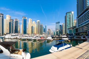 Naklejka premium Luxury boats and yachts line the interior harbor at the Dubai Marina, an affluent residential and commercial neighborhood along the Persian Gulf at Dubai, United Arab Emirates.