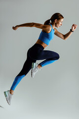 Woman running in Mid-Air exercising during cardio workout over studio background. High quality photo - obrazy, fototapety, plakaty
