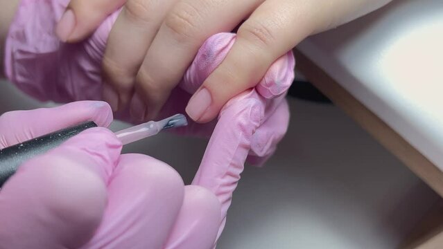 Manicure service of our own manufacture. Applying nude nail polish. manicure process. Application of nail polish on nails.