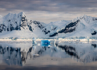 Impressive iceberg with blue ice and beautiful reflection on water in Antarctica, scenic landscape in Antarctic Peninsula	
