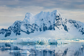 Impressive iceberg with blue ice and beautiful reflection on water in Antarctica, scenic landscape in Antarctic Peninsula	