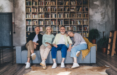 Group of haappy mature friends sitting on sofa and enjoying time in living room