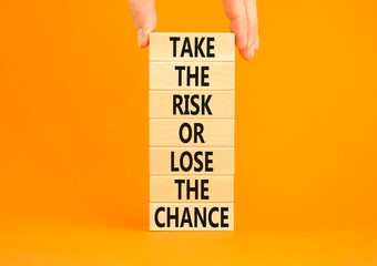 Risk or chance symbol. Concept words Take the risk or lose the chance on wooden blocks. Beautiful orange background. Copy space. Businessman hand. Motivational business risk or chance concept.