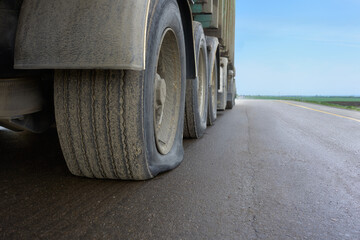 A flat tire on a large truck on a highway. View of a punctured truck wheel. A flat tire of a car on a road waiting to be repaired.