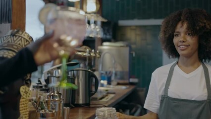 Video shot of African female bartender handing out a drink