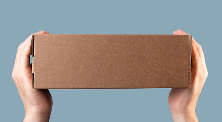 Hands holding brown cardboard box. Carton package mock-up, post order