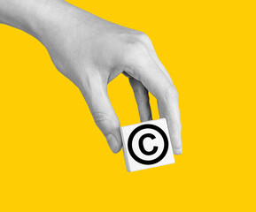 World copyright day. Hand with intellectual property protection, patent law sign in circle on cube