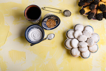 Traditional arabian cookies (kahk) sprinkled with white sugar and a cup of tea and petit four cookies
