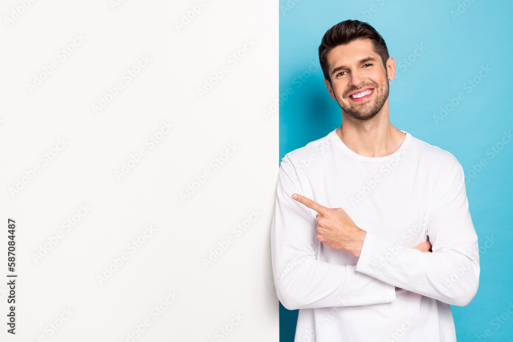 Poster photo of positive glad person beaming smile indicate finger empty space blank isolated on blue color