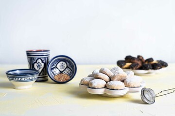 Traditional arabian cookies (kahk) sprinkled with white sugar and a cup of tea and petit four...