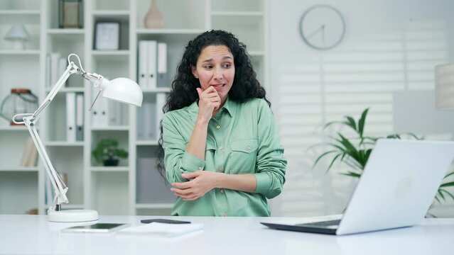 pretty young woman office worker employee showing oops gesture while sitting at workplace Confused puzzled business female Looking camera spreading hands work laptop spread hands shrugging shoulders