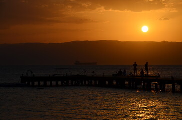 Fototapeta na wymiar A couple against the sunset on a pier in Aqaba on the Red Sea
