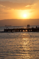 Naklejka na ściany i meble A couple against the sunset on a pier in Aqaba on the Red Sea