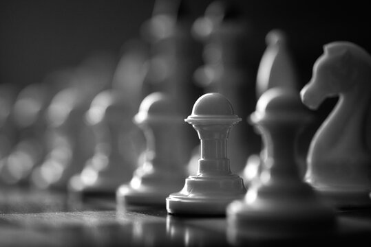 a pawn chess piece among white chess pieces on the board