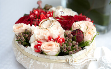 Bouquet of the bride with wedding rings close-up. Wedding bouquet of beige, white and bright red roses. Wedding decor