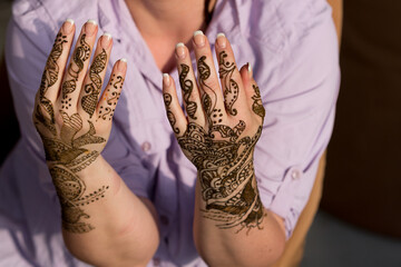 woman allows henna dye to take effect in traditional patterns on her hand 