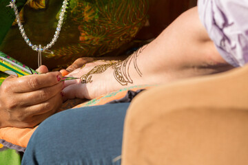 woman applies traditional patterns with henna to another woman's hands