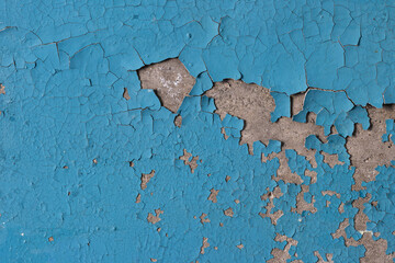 Blue peeling paint on the wall. Old concrete wall with cracked flaking paint. Weathered rough...