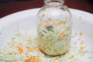 Cooking sauerkraut at home. A glass jar stands in shredded cabbage