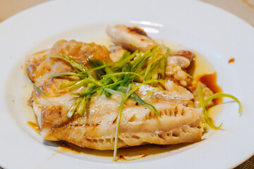Steamed fish in black bean sauce arranged in a white plate