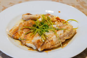 Steamed fish in black bean sauce arranged in a white plate