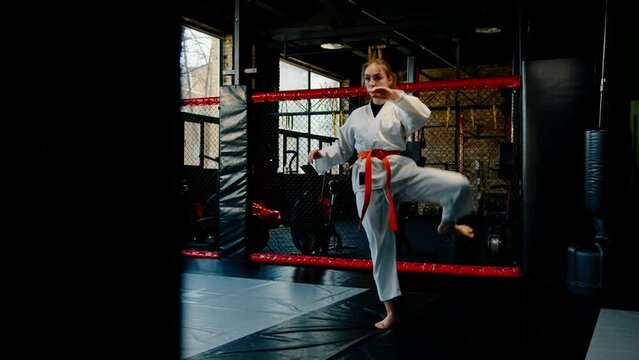 A girl practices karate in a gym A woman in kimono practices movements and poses Martial arts