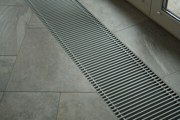 Heating grill with ventilation in the floor in laminate.. Forced hot-air heating systems are extremely popular and feature vents like this to channel the hot air throughout the house.