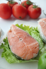 Raw, fresh salmon steak and tomato on table 