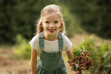 little girl with a bouquet of wild strawberries