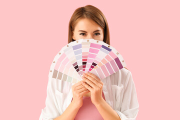 Beautiful woman with paint color palettes on pink background