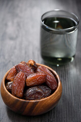 dried dates in a bowl and a glass of water behind it. In Islam, it is consumed to break the fast.