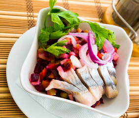 Popular russian salad Vinegret with chopped roots, vegetables, herring and onion rings