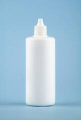 White medical liquid container on light blue background. Plastic blank bottle health care and medical top view on colored blue background.